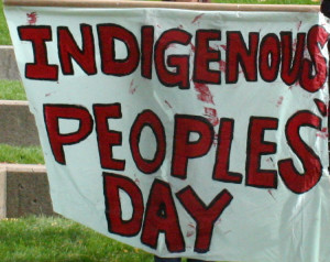 This is a photograph of a white banner that says "Indigenous People's Day" in red paint.