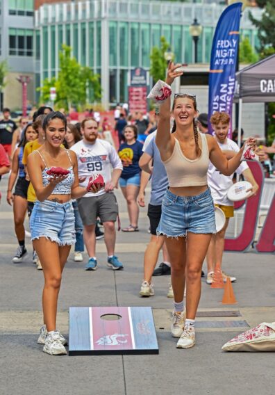 two students toss bean bags in a game of cornhole at WSU's all campus picnic