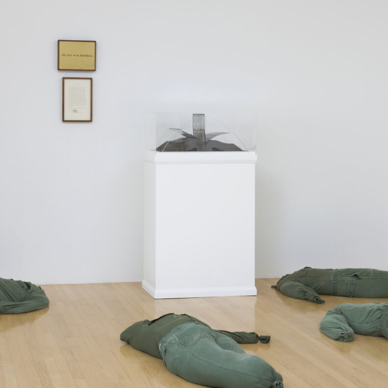 Stuffed clothing laying on a gallery floor with a display of an open book.