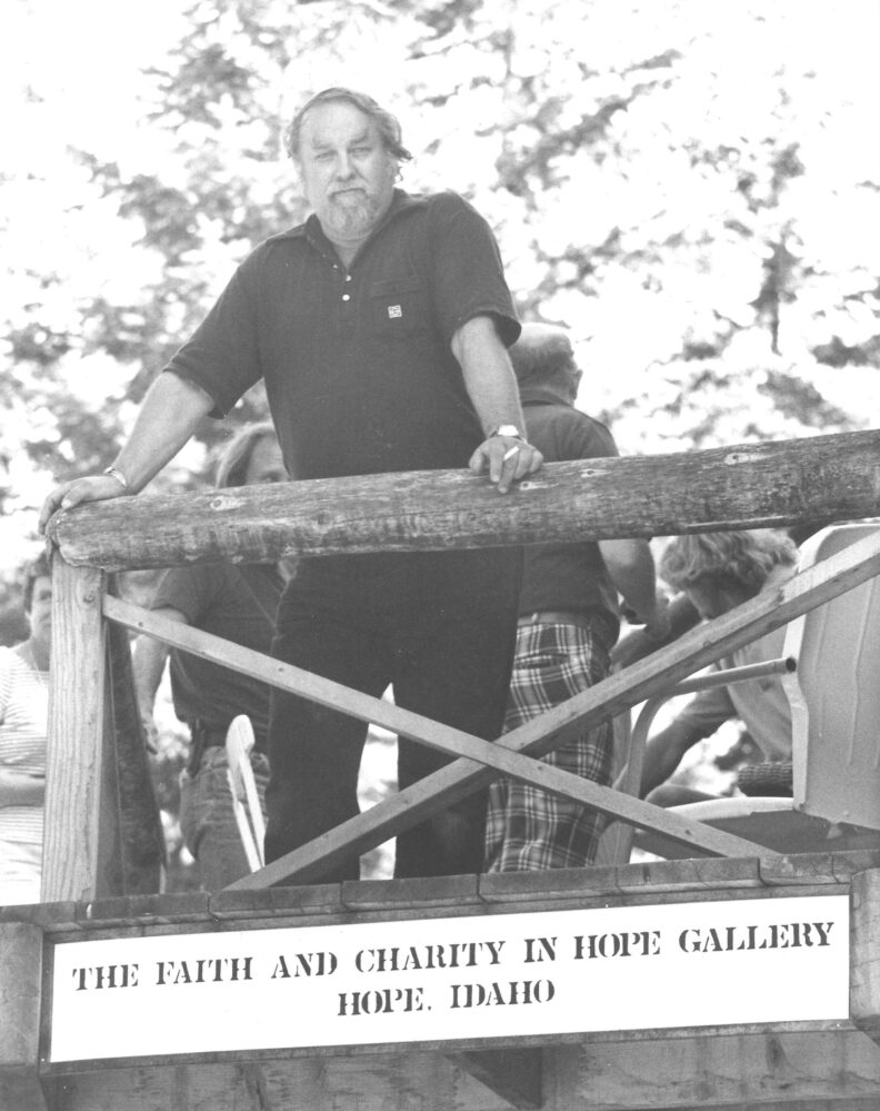 Black and white photo, a man leans on a wooden railing.