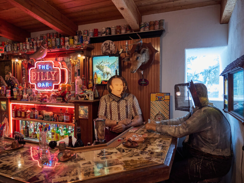 Photo of an art installation of a bar, facing mannequin's at the bar.