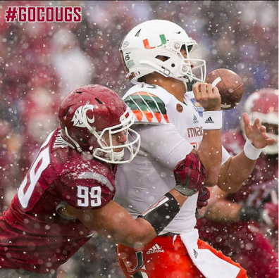 A WSU football player tackling a University of Miami football player in the snow.