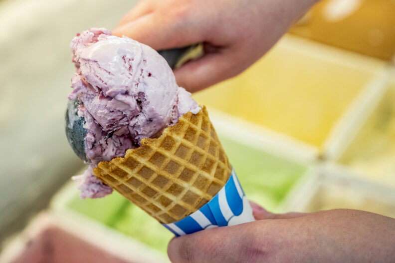 A Ferdinand's worker scoops up huckleberry ice cream into a waffle cone.