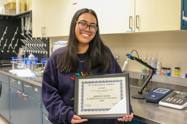 Sherine Ortiz smiles and holds up her award.