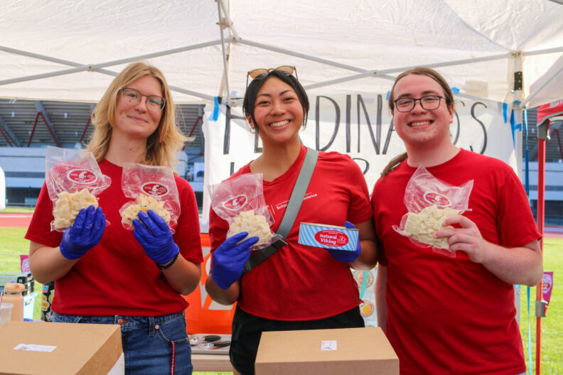 Three food science students, including Natalie, hold up cheese in bags and a can. 