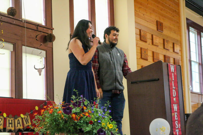 Natalie speaks at the podium beside her co-host.