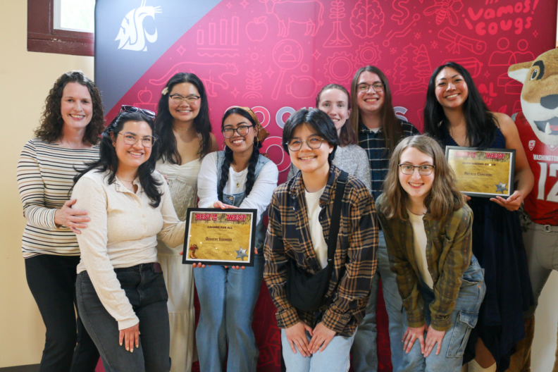 A group of people gathered in front of a red background for a picture.