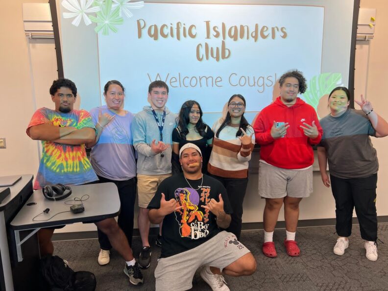 Sherine and a group of others stand in front of a PowerPoint slide that says, "Pacific Islanders Club. Welcome Cougs!"