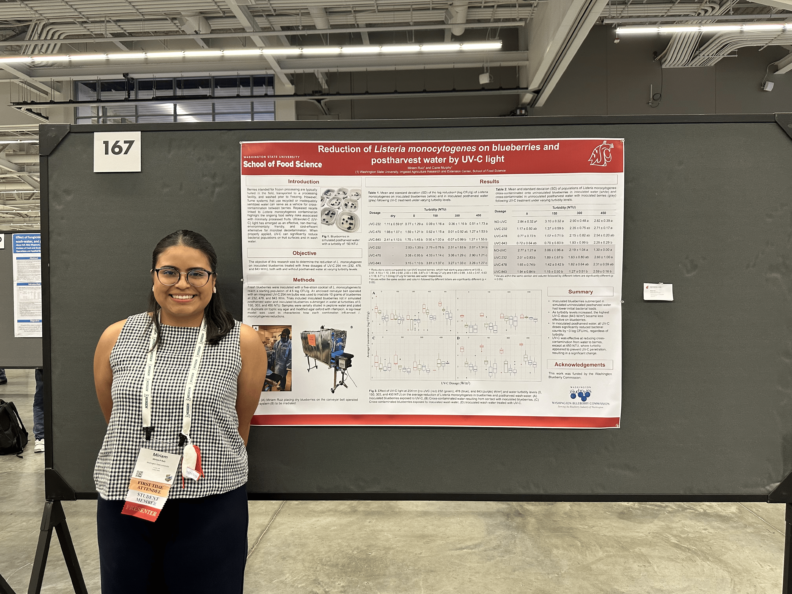Miriam stands in front of her research poster.