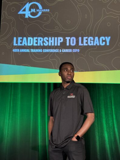 Paul stands beneath a sign that says, "Leadership to Legacy."