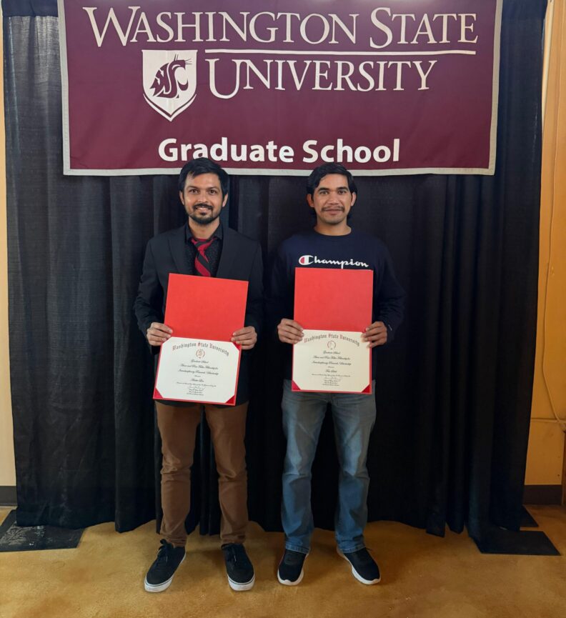 Aniket and Sahil hold up their awards. Behind them is a banner that says, "Washington State University. Graduate School."