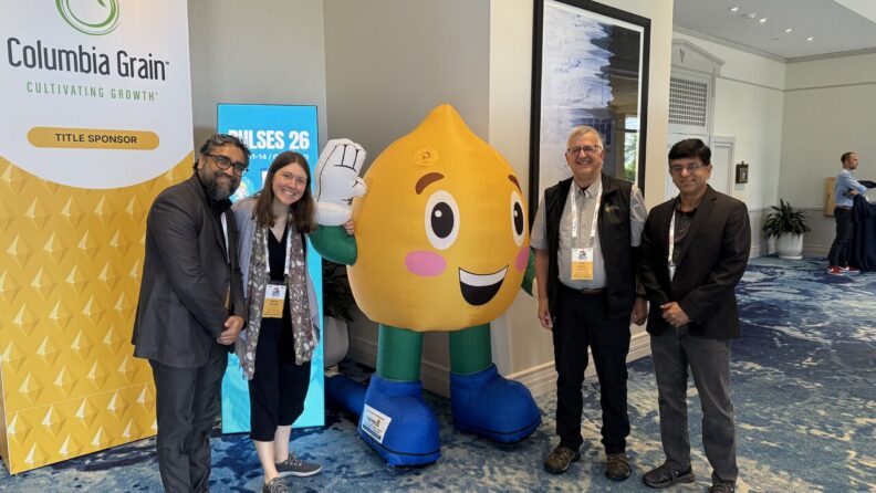 Dr. Ganjyal and other attendees of the conference stand next to an inflated, anthropomorphized chickpea.