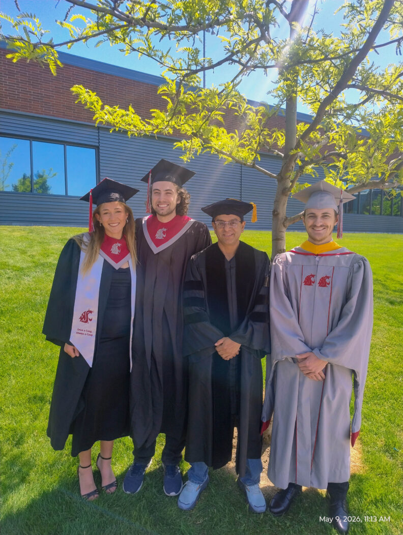 Three graduating students and their professor, Girish Ganjyal, stand in a line together.