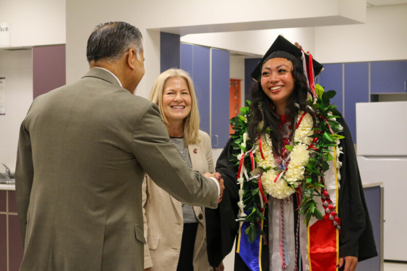 Undergrad Natalie Camerino shakes hands with Dean Raj Kohsla. Nancy Deringer stands between them.