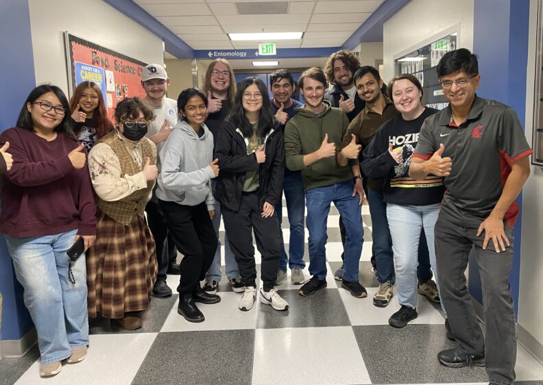 The Ganjyal lab standing in a group in the hallway. They all give a thumbs up and a smile.