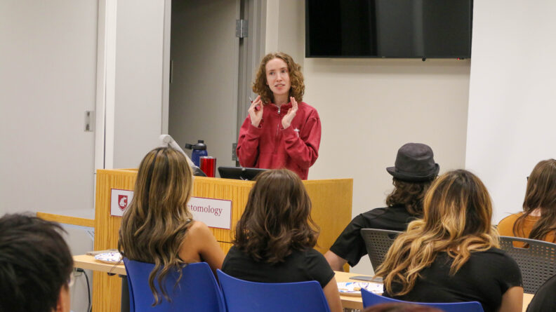 Rachel stands at a podium. Students are seated in front of her.