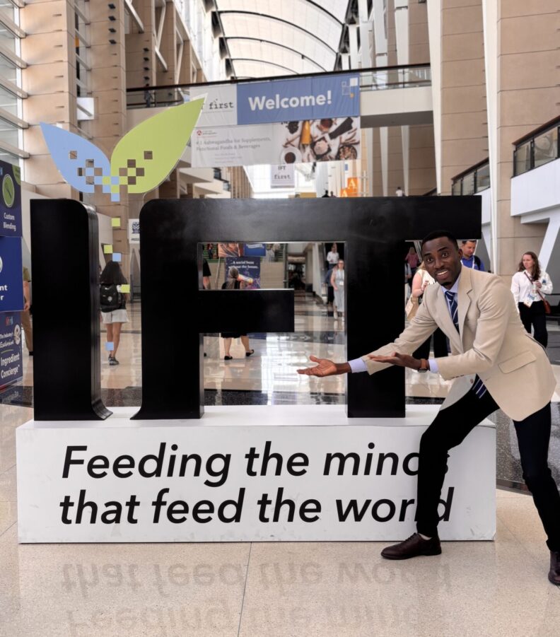 Paul gestures to a sign that says, "IFT. Feeding the minds that feed the world."