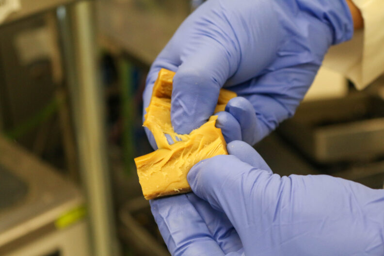 Gloved hands tear apart fibrous extruded material. 