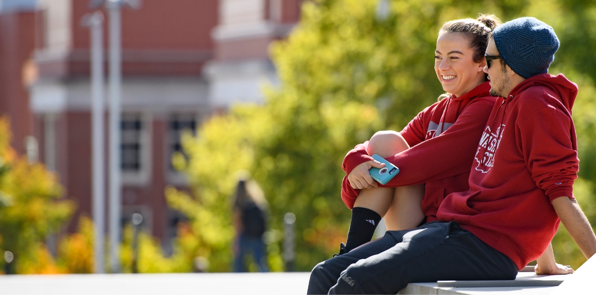 A male and female student sitting and smiling.