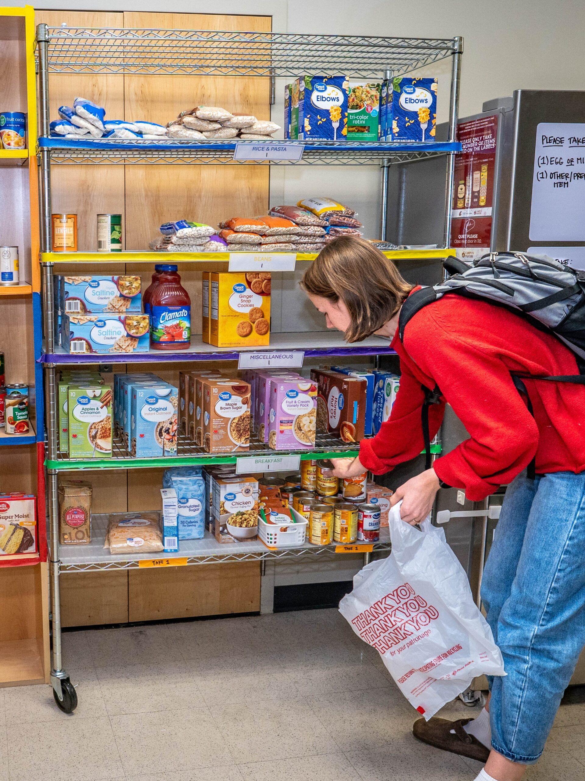 A student with a grocery bag in a food pantry.