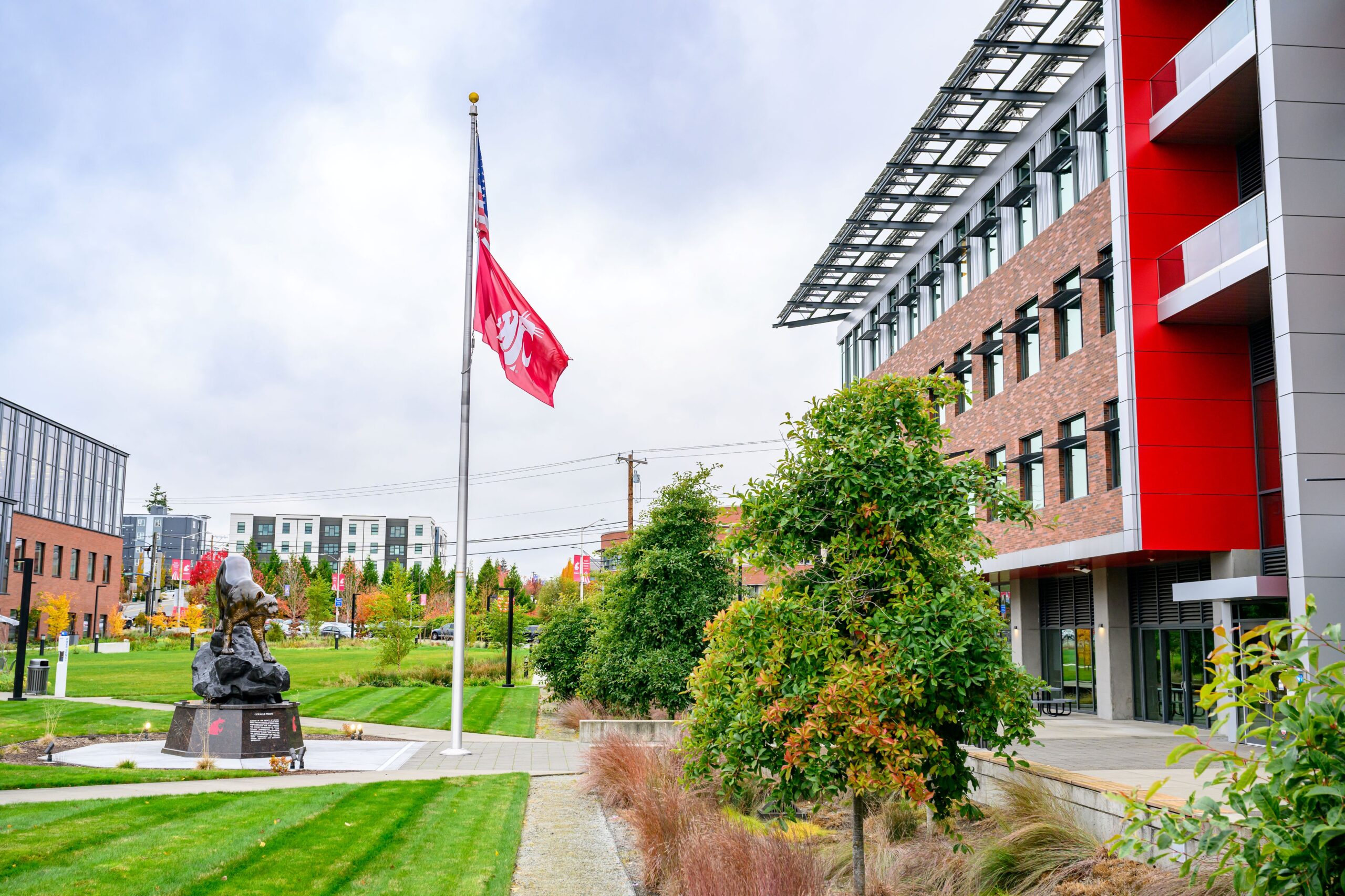 WSU Everett campus with Coug statue and US and Coug flag flying on a flag pole.