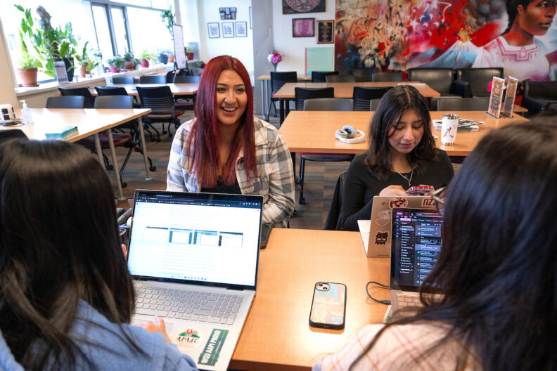 Students in the ChicanX/LatinX student center laughing with laptops.