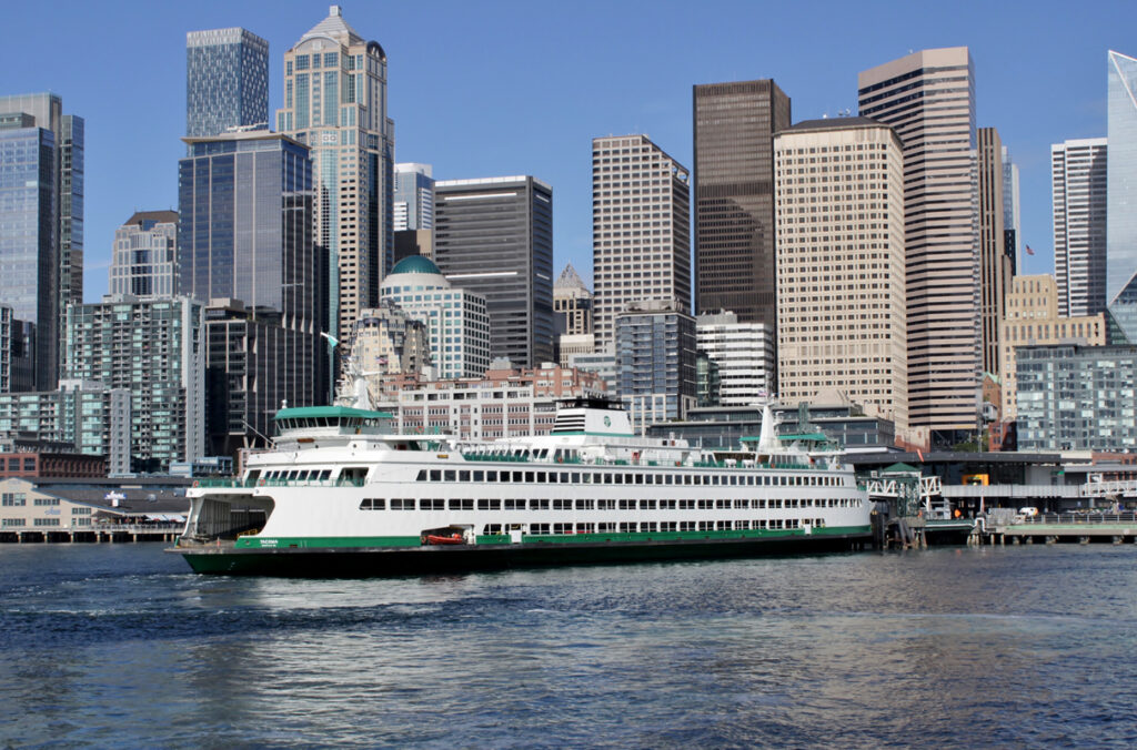 A Washington state ferry on the water with the Seattle skyline in the background.