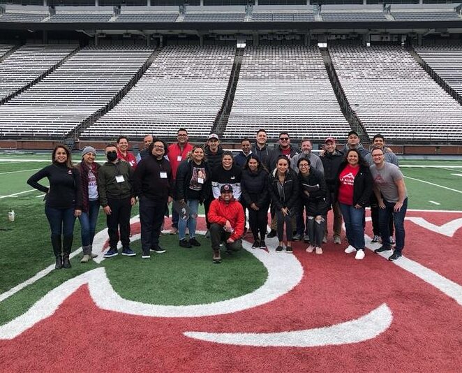 A group photo of La Alianza de WSU community members standing on the WSU football field.