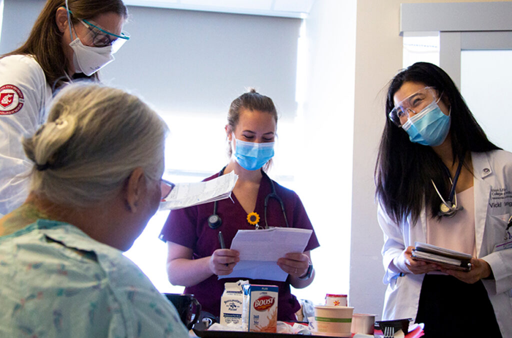 Three critical care physicians visiting with an elderly patient.