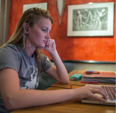 A student sitting at their desk, looking at their laptop