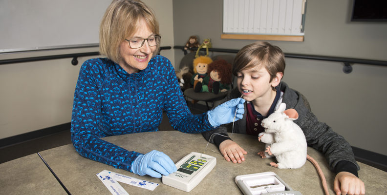 Nancy Potter uses a device that measures tongue strength on a young boy.