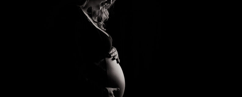 Silhouette of pregnant woman holding growing belly
