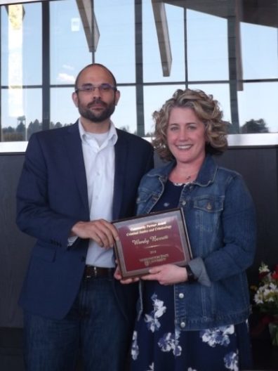 Dr. David Makin hands an award placque to Wendy Berrett.