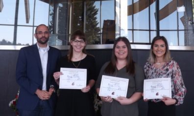 Dr. David Makin stands with students Staci Friede, Emily Martin, & Isobel Luengas, who are displaying their award certificates..