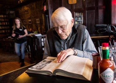 Jim Short is sitting at a table in Rico's Pub browsing through the encyclopedia.