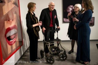 Jim Short stands and converses with three other people in the museum.