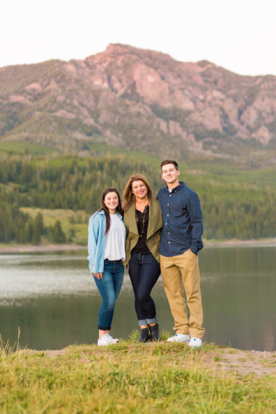 A photo of Amy Cox and her two children standing outside and smiling at the camera.
