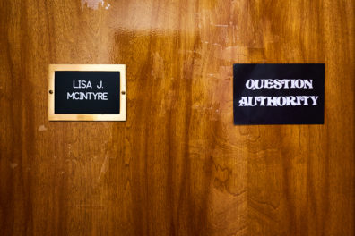 Lisa McIntyre's office door with her name placard and a sticker which says, "Question Authority."