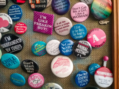 A close up photo of a cork board full of colorful pins and buttons.