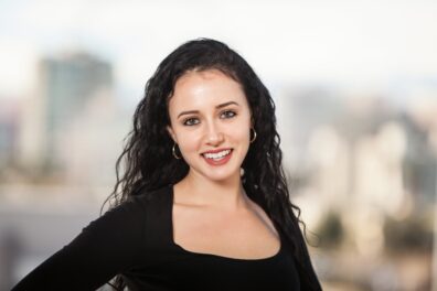 A front facing photo of Shekinah Hoffman, from the shoulders up. She is looking into the camera and smiling.
