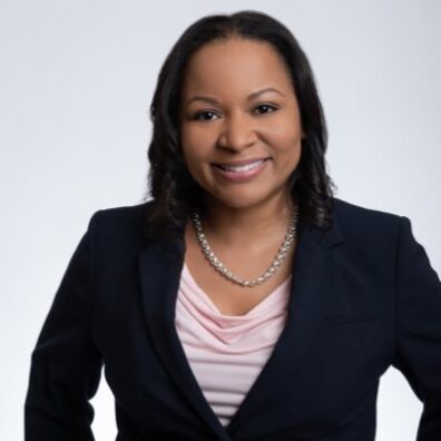 Juanita is pictured from the waist up and smiling.
