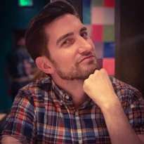 Matt is pictured with his chin resting on his balled first and softly smirking.