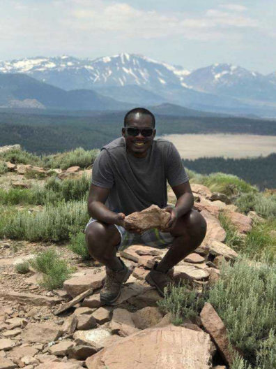 Lambert Ngenzi in the California White Mountains holding a rock with the mountains in the background.
