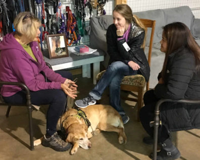 Two female student visit with lady with pet dog in the foreground