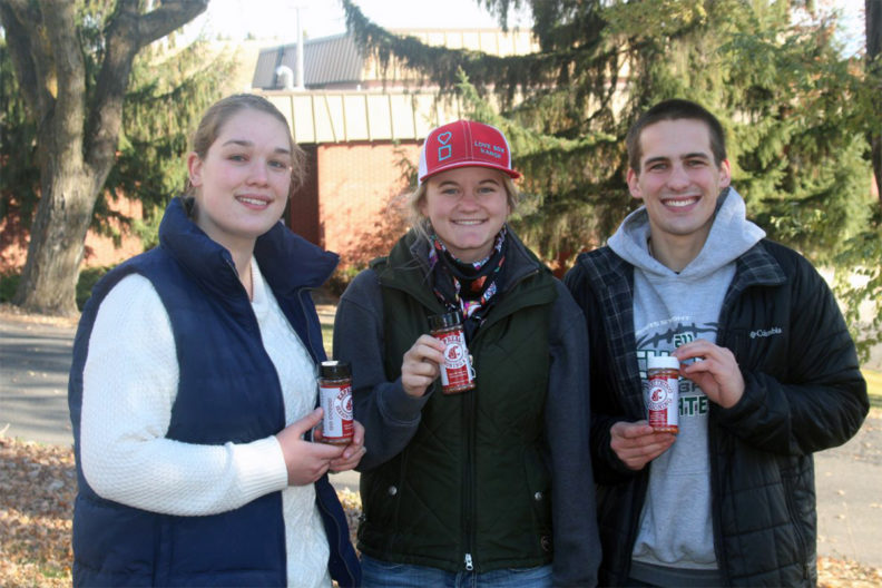 Three students holding seasoning side by side.