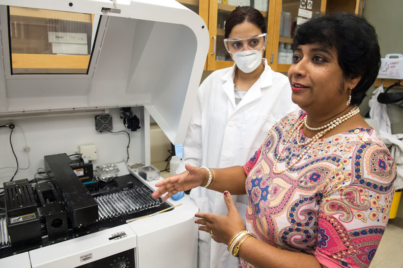 Susmita Bose talking to lab assistance next to a machine