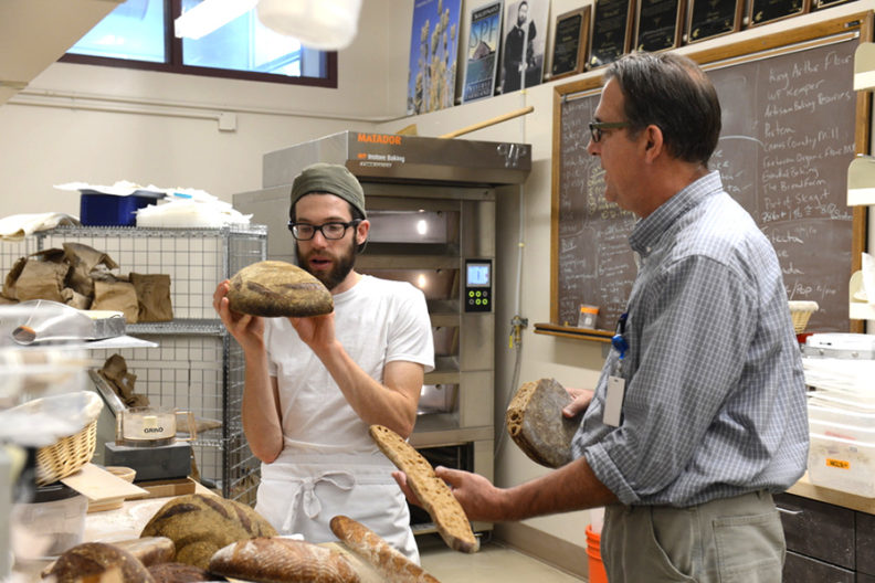 Stephen Jones examines different breads with a bread lab student