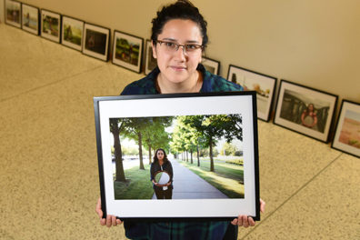 Susanna Butterworth standing in profile with framed photography