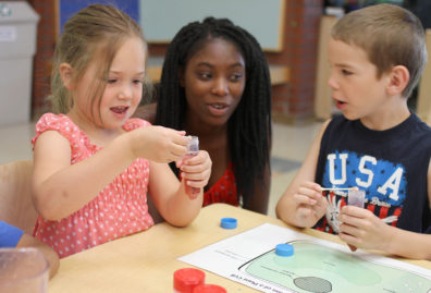 Two young kids and their caregiver with test tubes activity learning about plants and science.