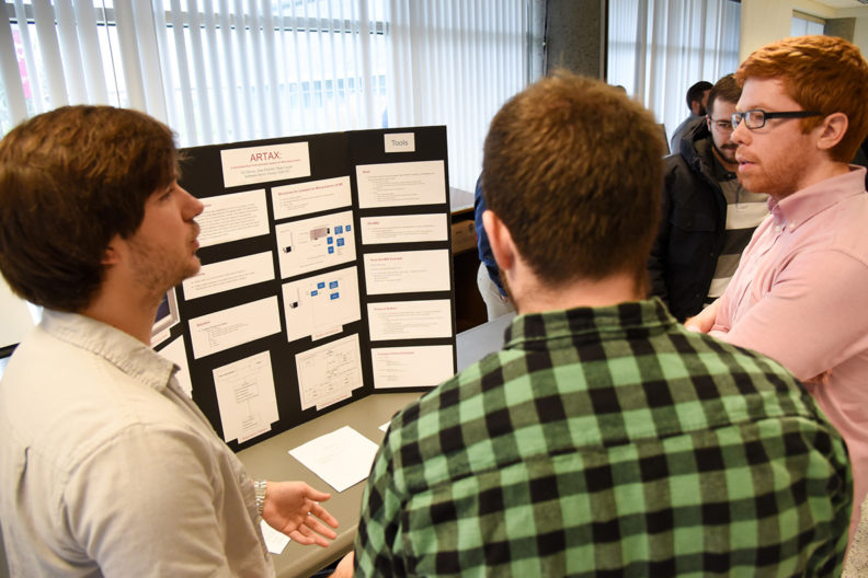 Three students in front of poster board